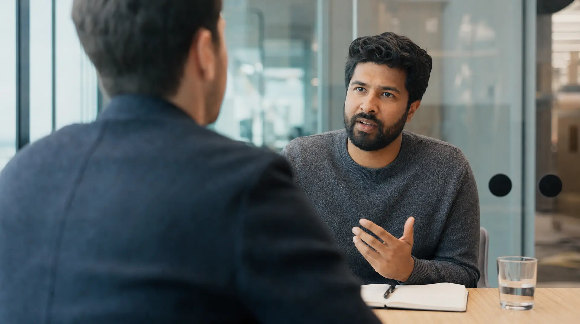 Two professionals meet at a conference table in a modern office, supporting the recruitment process and improving candidate experience during discussion.