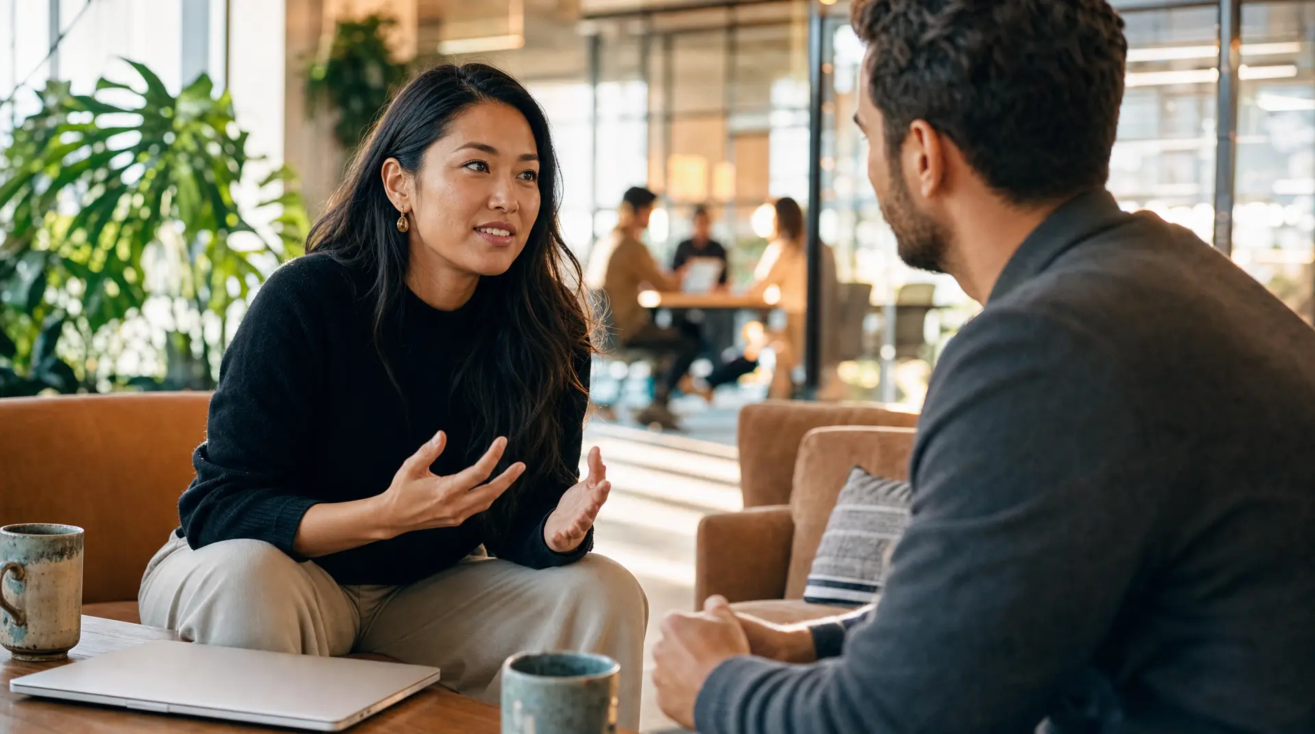 Woman and interviewer sit across from each other at a table in a bright office with a laptop, supporting improve candidate experience in recruitment.