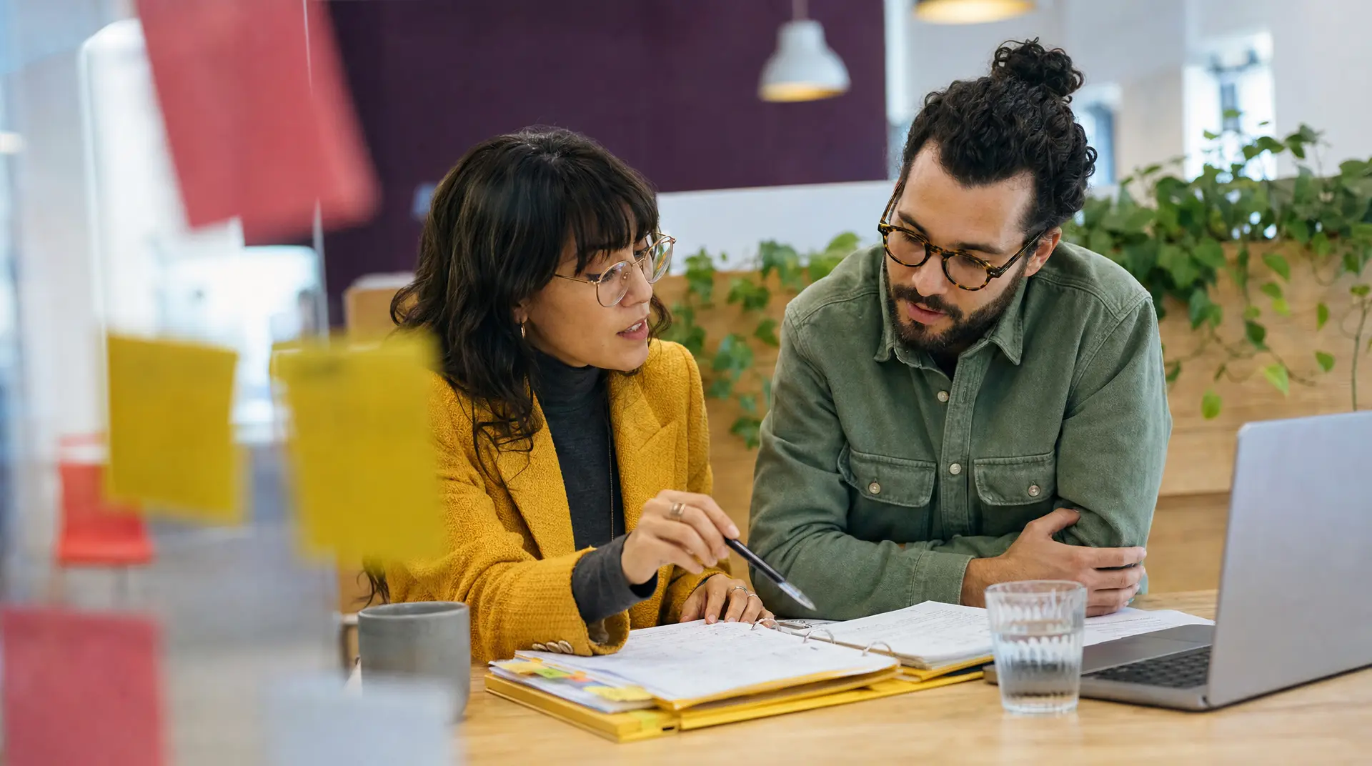 Two professionals review documents at a desk, aligning talent acquisition and recruitment steps in a modern office setting.