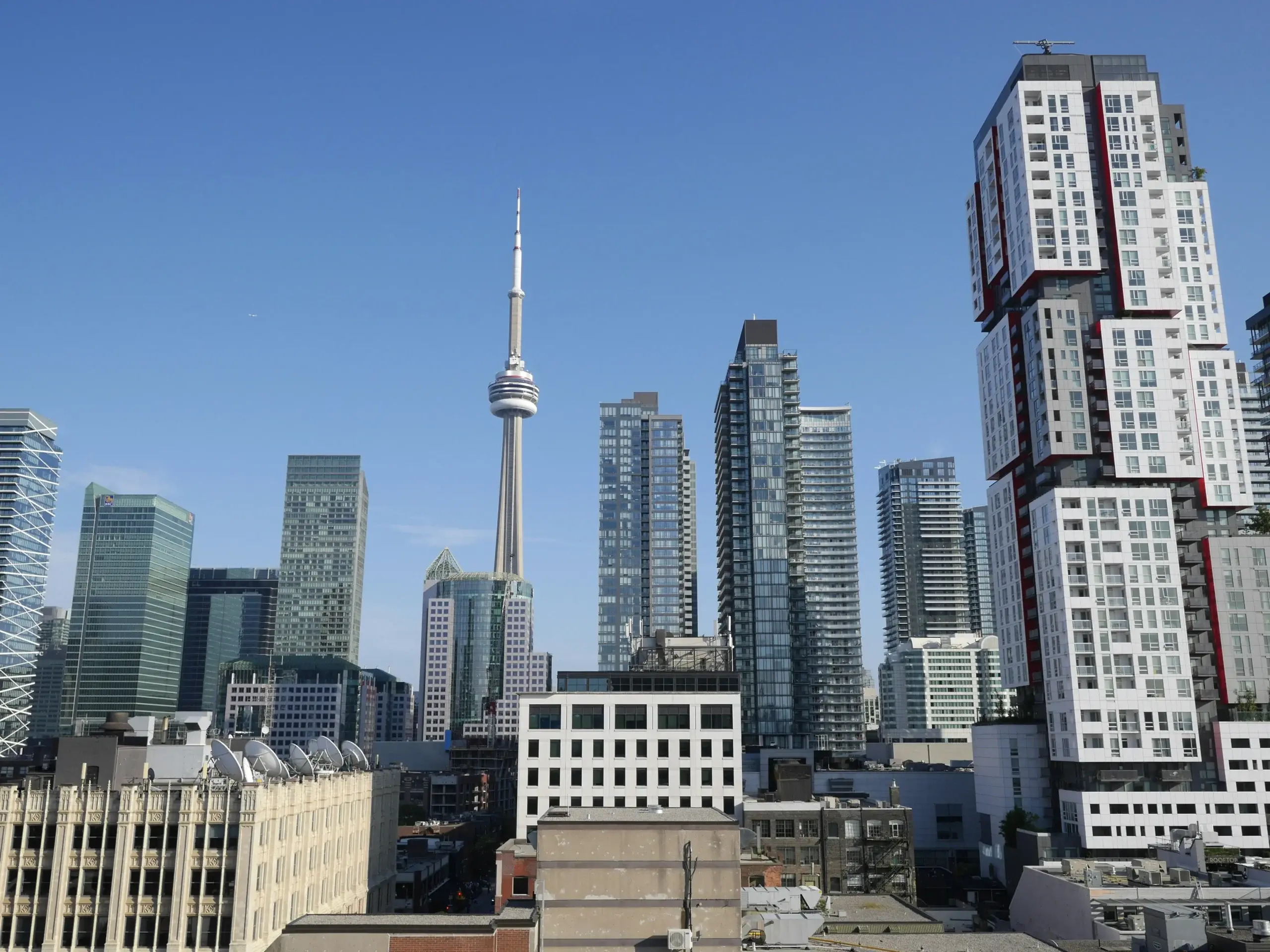 Downtown skyline with a tall communications tower and dense high-rise apartment buildings against a clear blue sky, reflecting talent acquisition planning.
