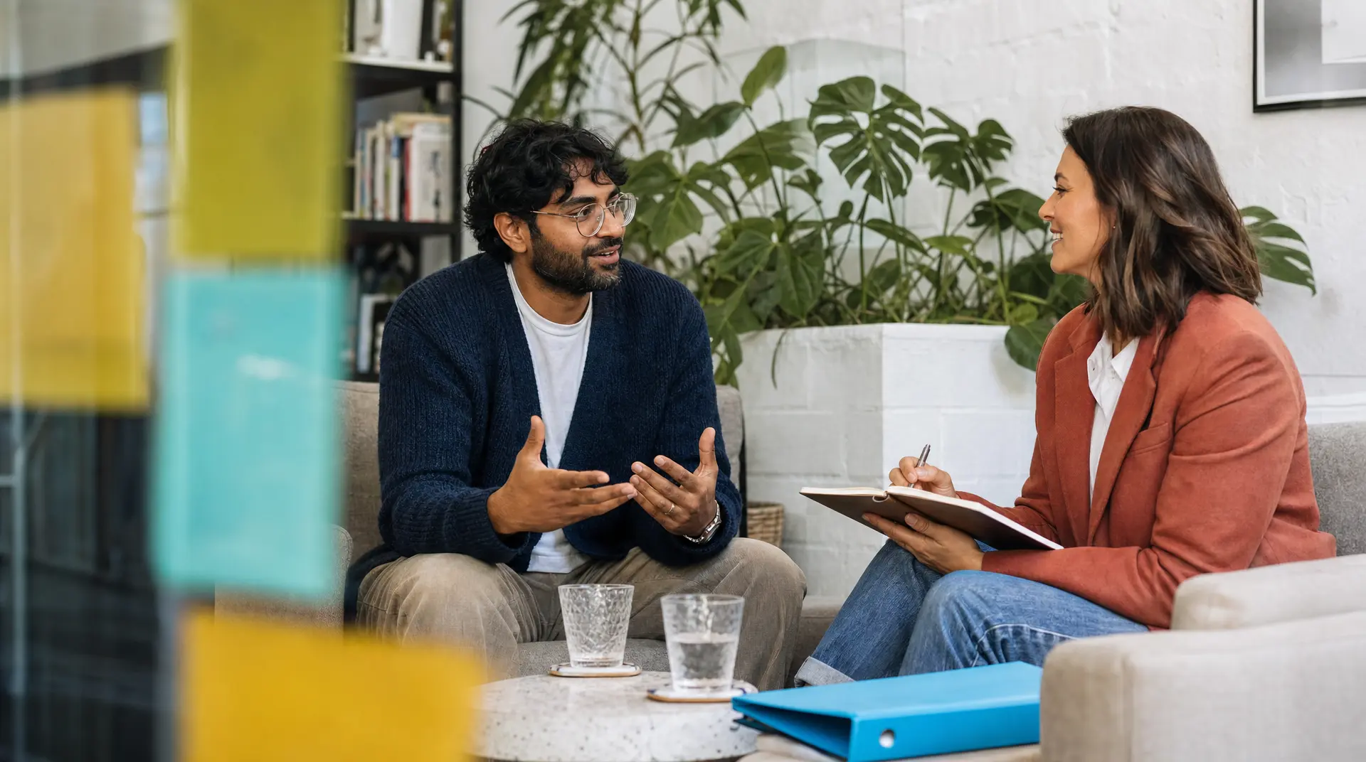 A recruiter and candidate sit facing each other in a bright office, discussing recruitment screening and talent acquisition during an interview.