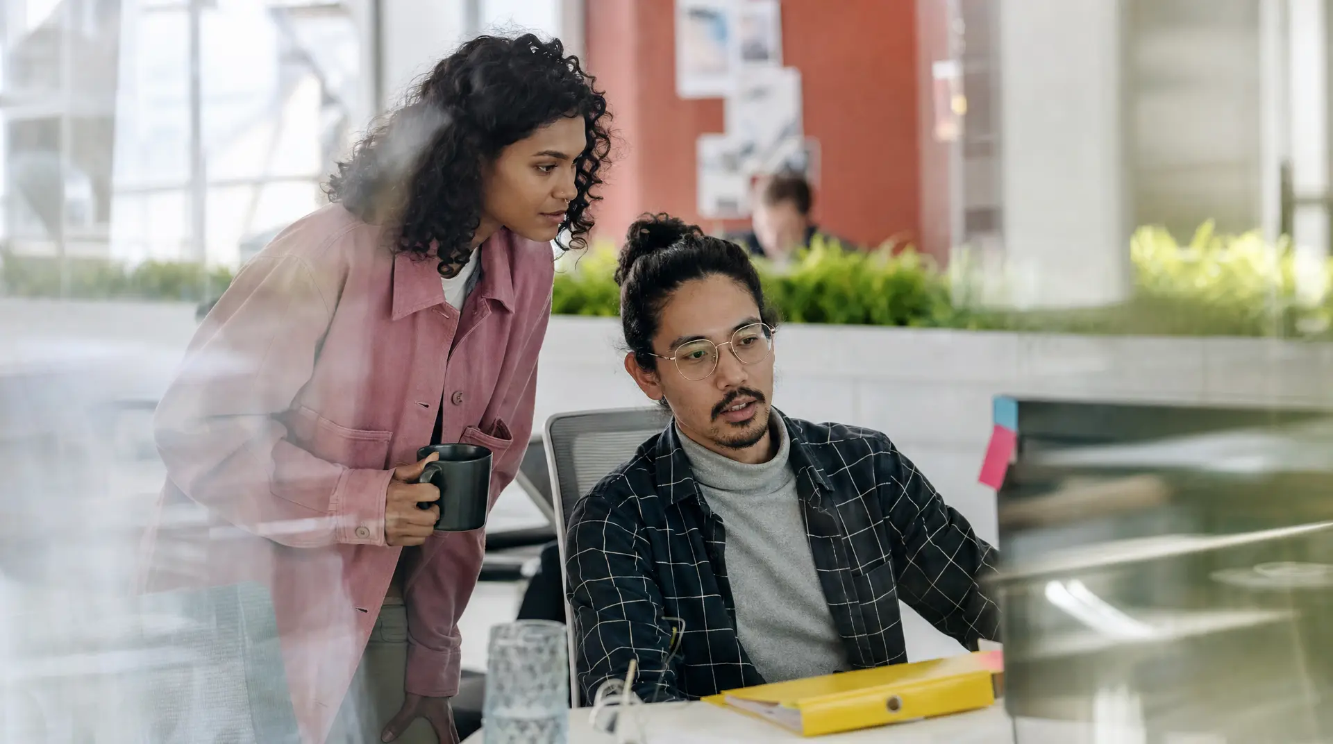 Two colleagues collaborate at a table in a bright office, discussing talent acquisition and the recruitment process with a focused, meeting-ready demeanor.