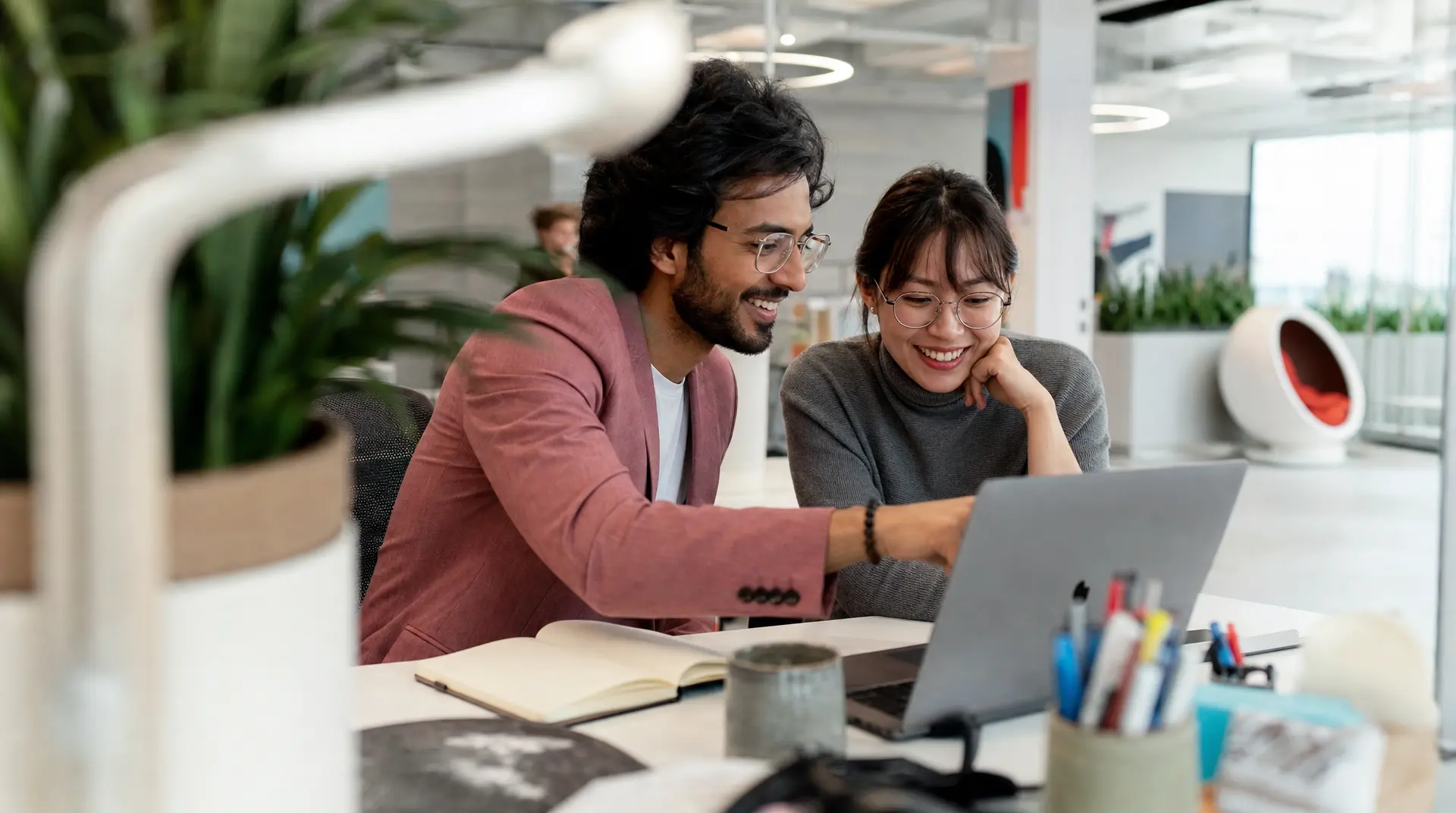 Two colleagues review a laptop together in a bright office, reflecting talent acquisition planning supported by AI in hiring workflows.