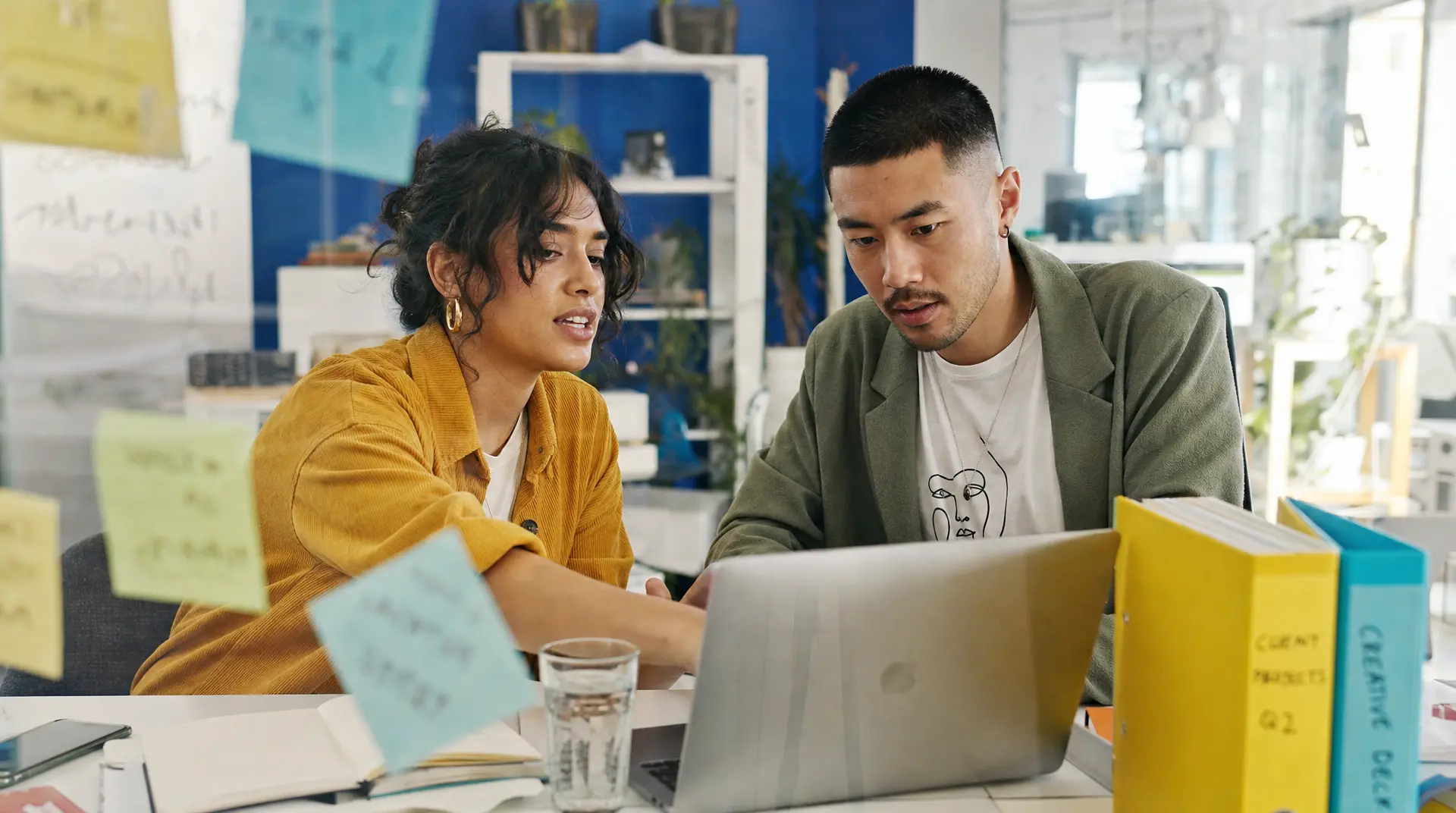 Two professionals review information on a laptop at a shared desk in a bright office, reflecting the recruitment process workflow.