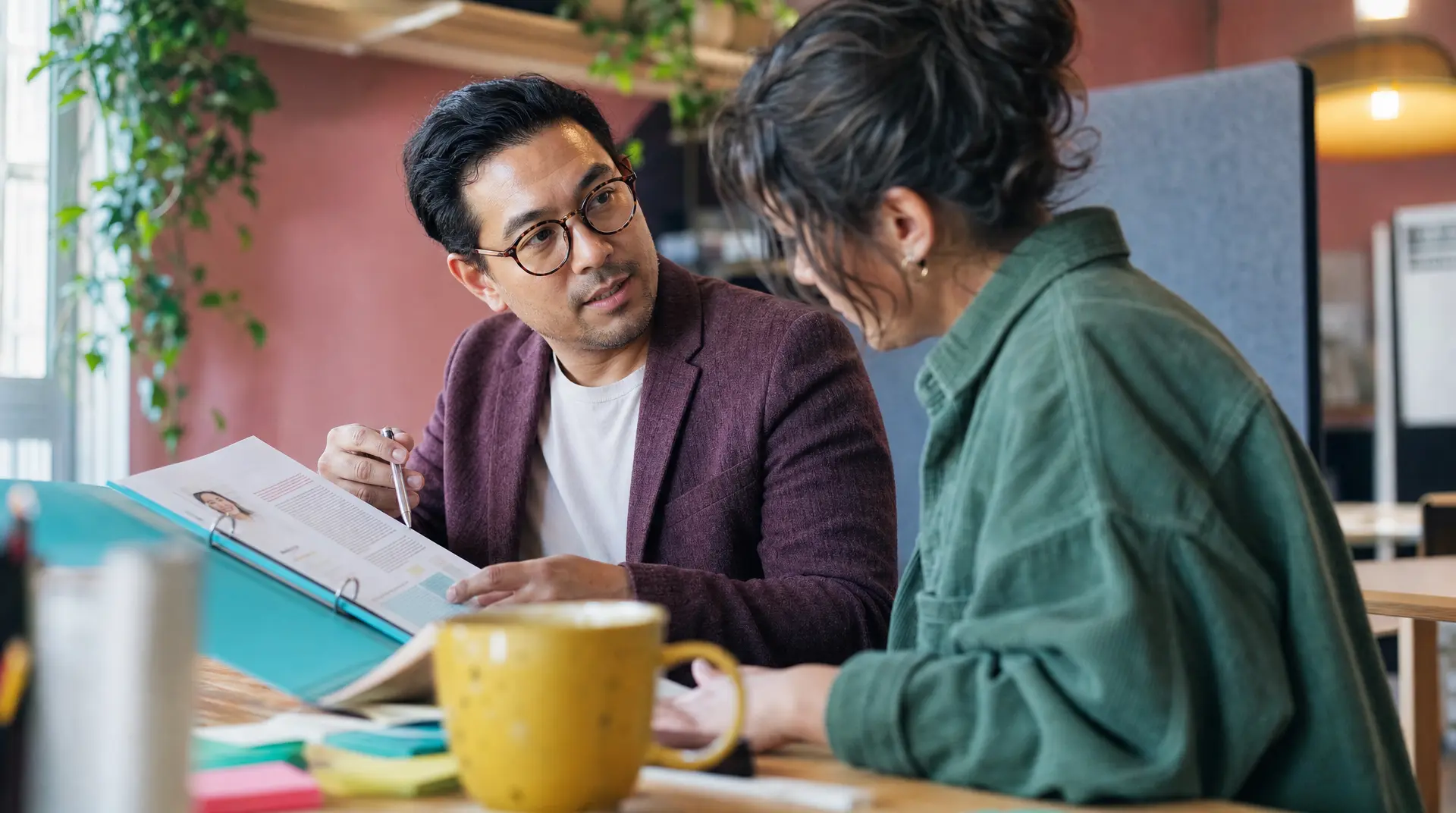 A recruiter speaks with a prospective hire at a conference table while reviewing assessment tools for recruitment documents in an office setting.